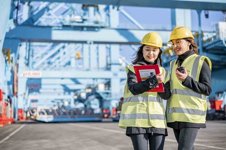 Two women at work at a harbor dock wearing protective clothing