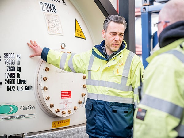 Tank container specialist standing next to gas tank container